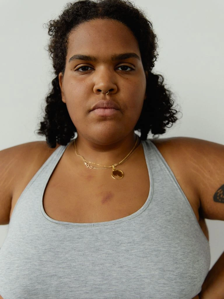 Curvy model in a burgundy bra, framed chest-and-up, looking directly at the camera